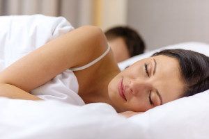 A woman is sleeping in a bed next to a man.