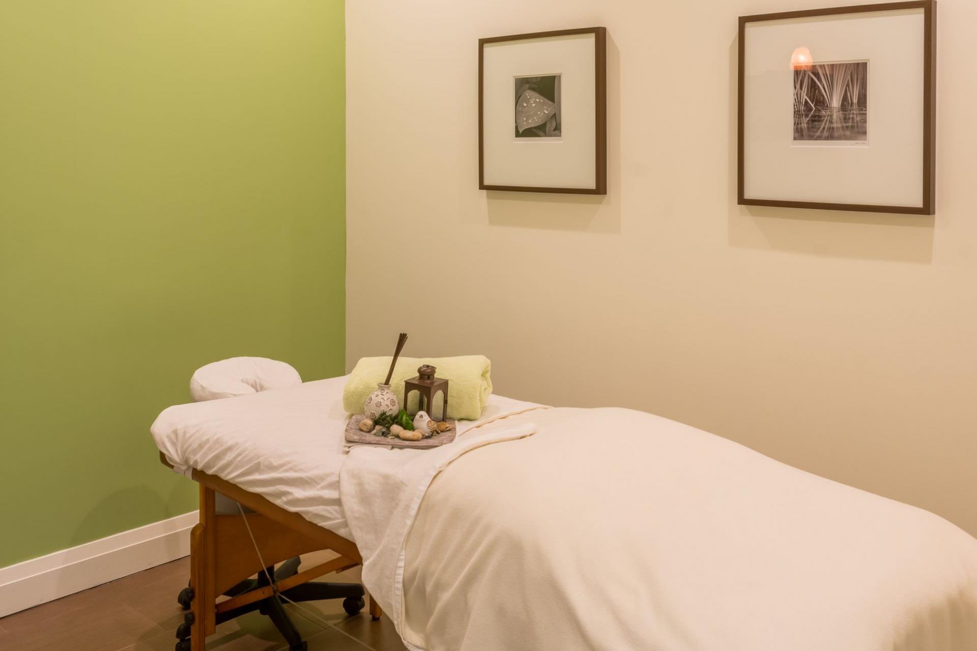 Massage table in a calm spa room with green accent wall and framed art.