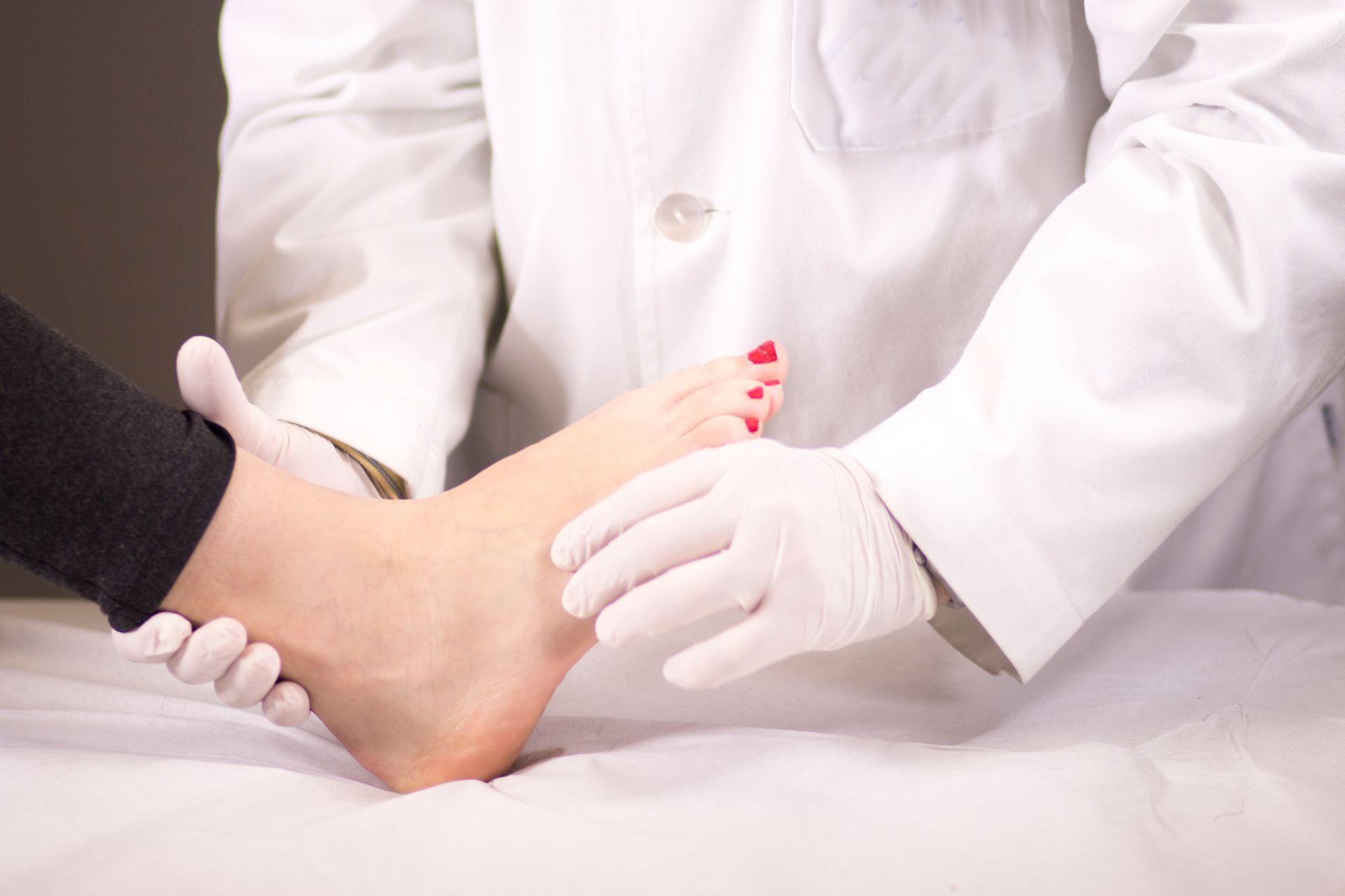 Healthcare worker examining a foot with gloved hands on a treatment table