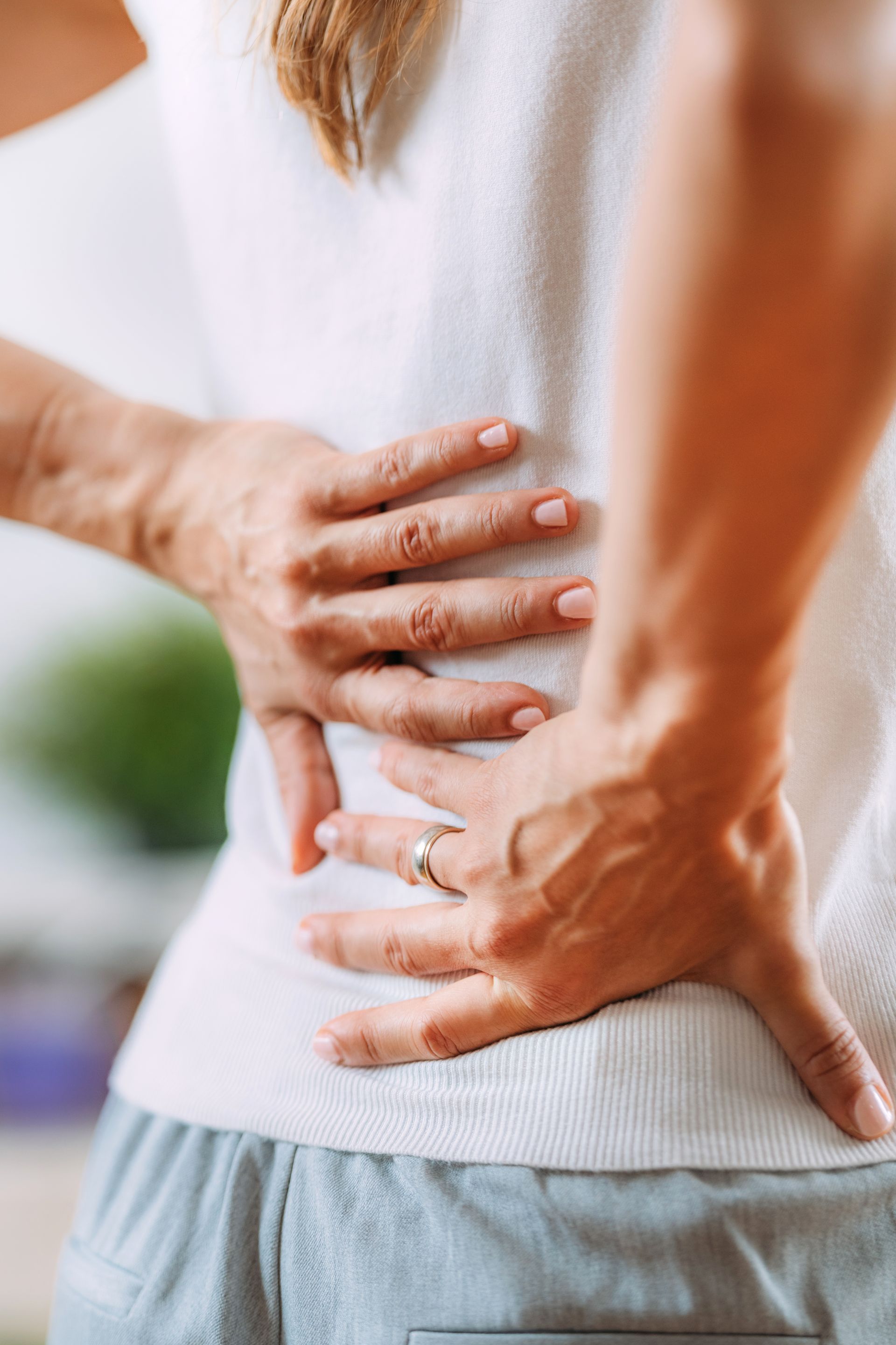 A woman is holding her back in pain.