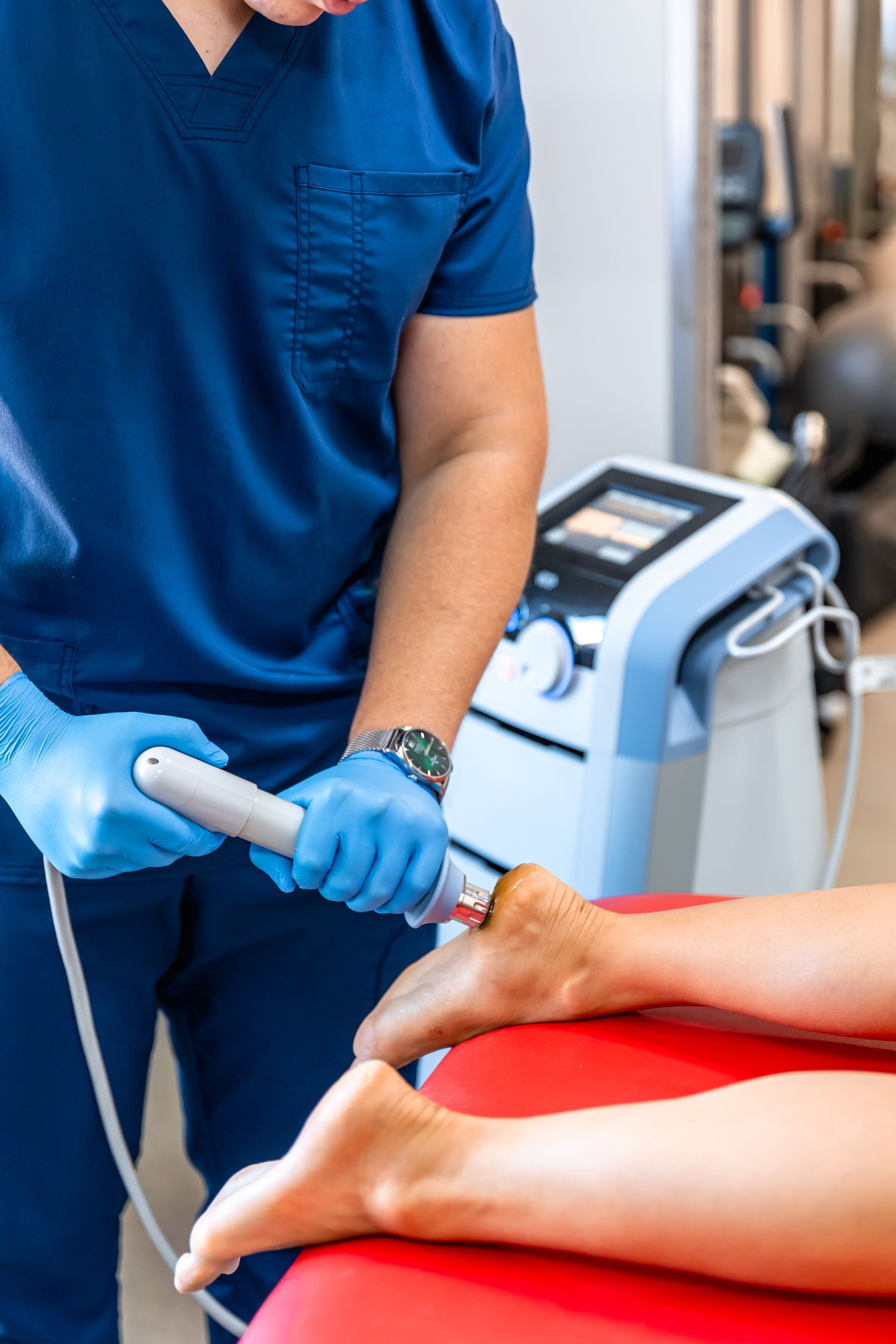 A doctor is using a machine on a patient 's foot.