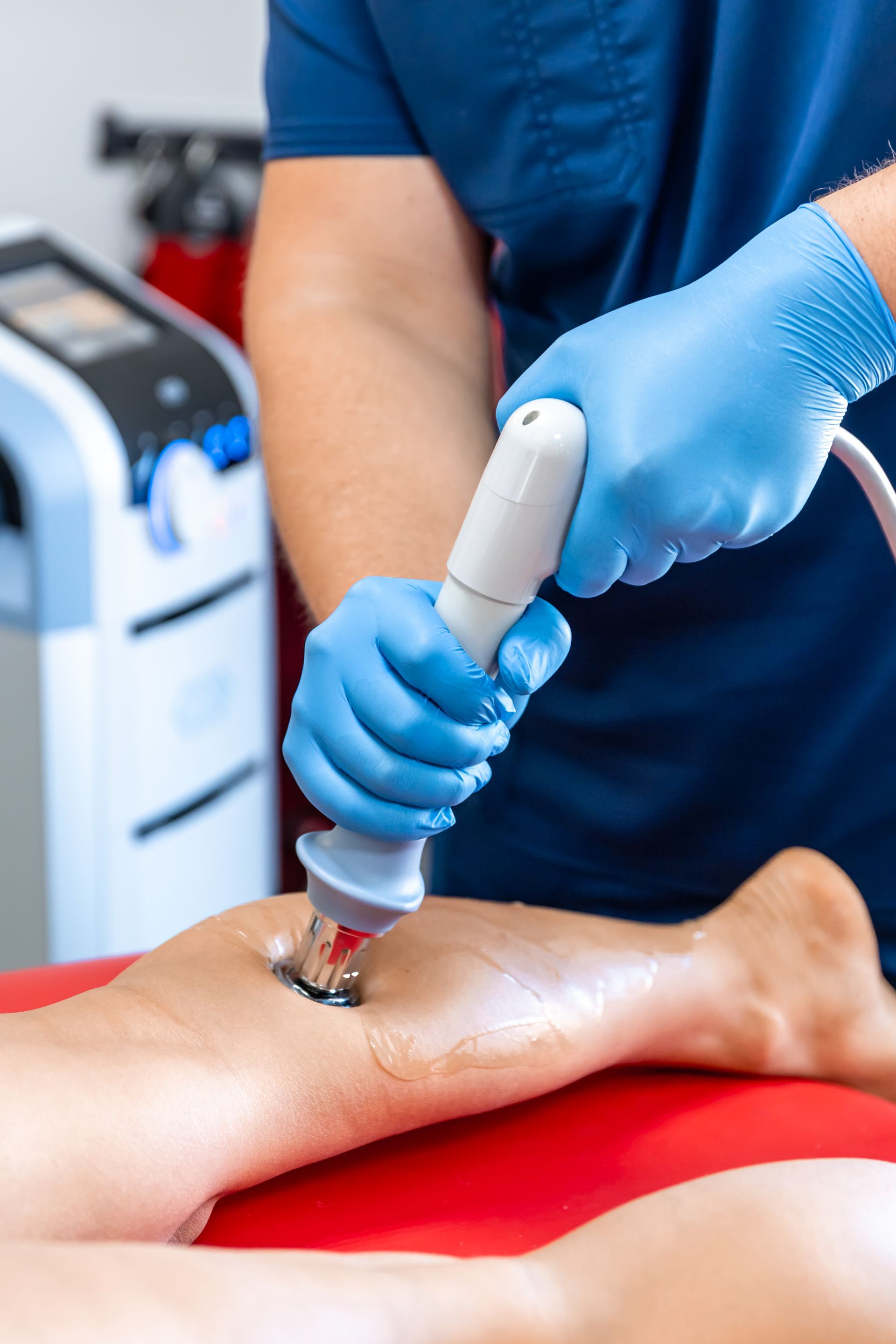 A doctor is using a machine on a patient 's leg.