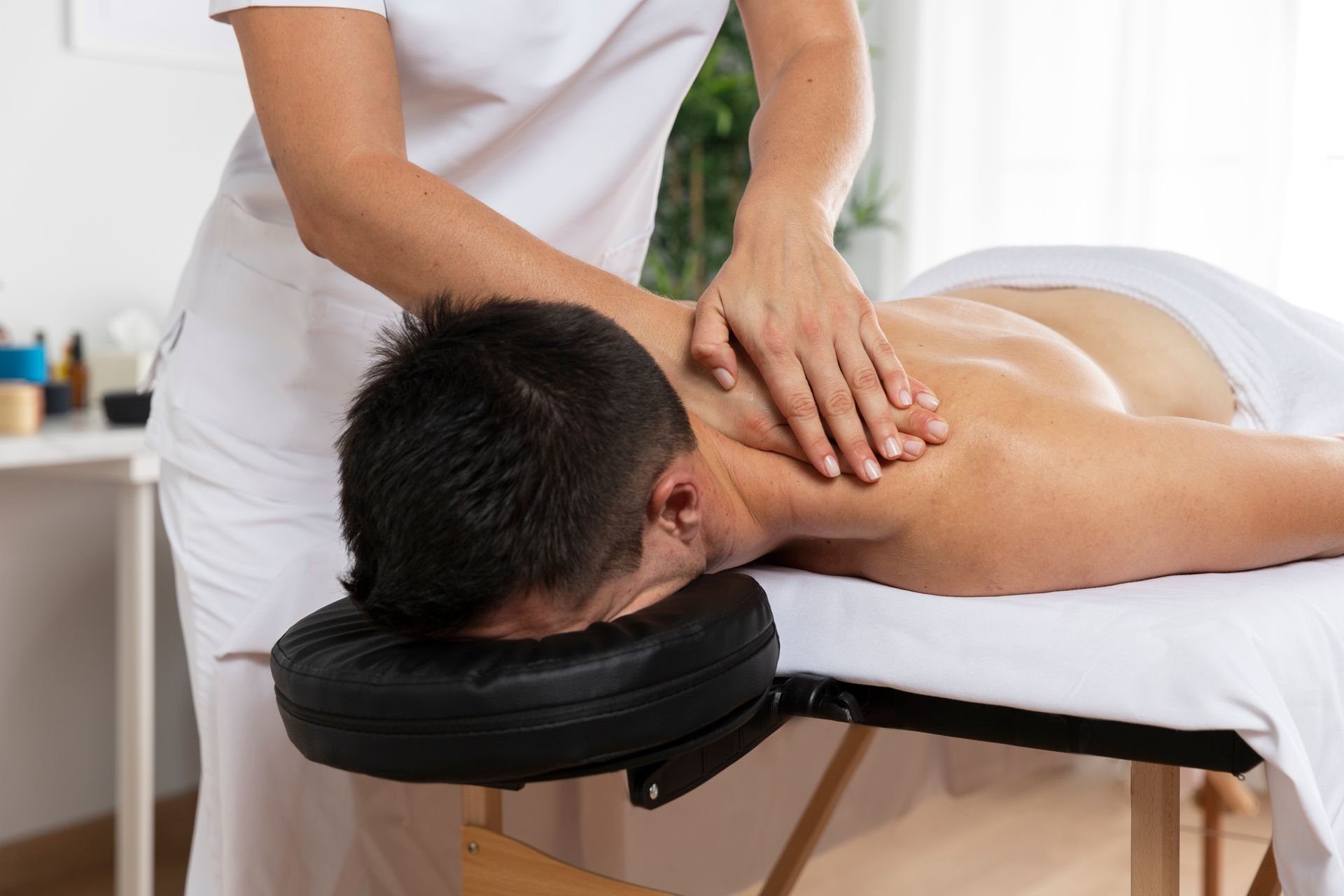 A man is laying on a bed getting a massage.