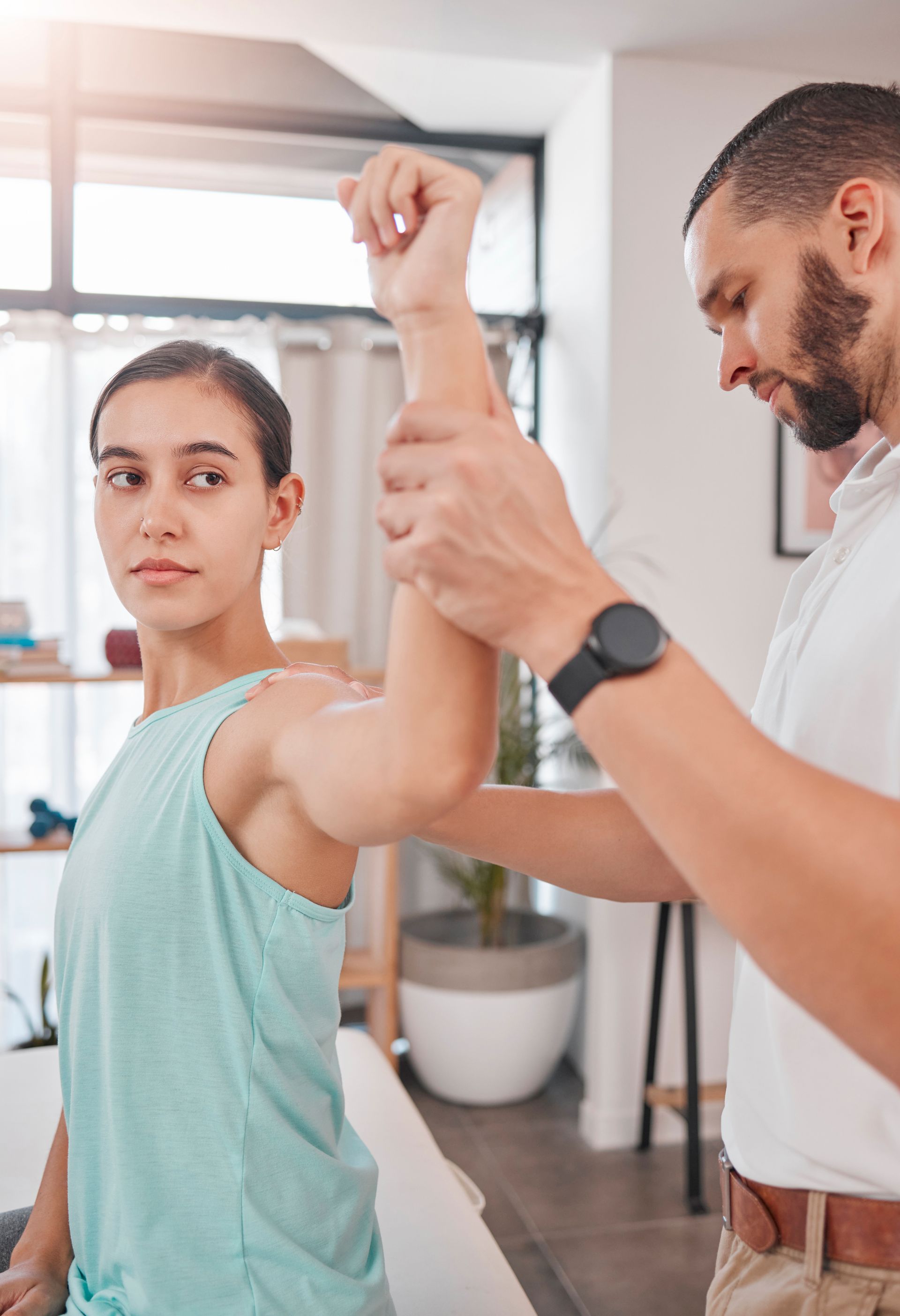 A man is examining a woman 's arm in a room.
