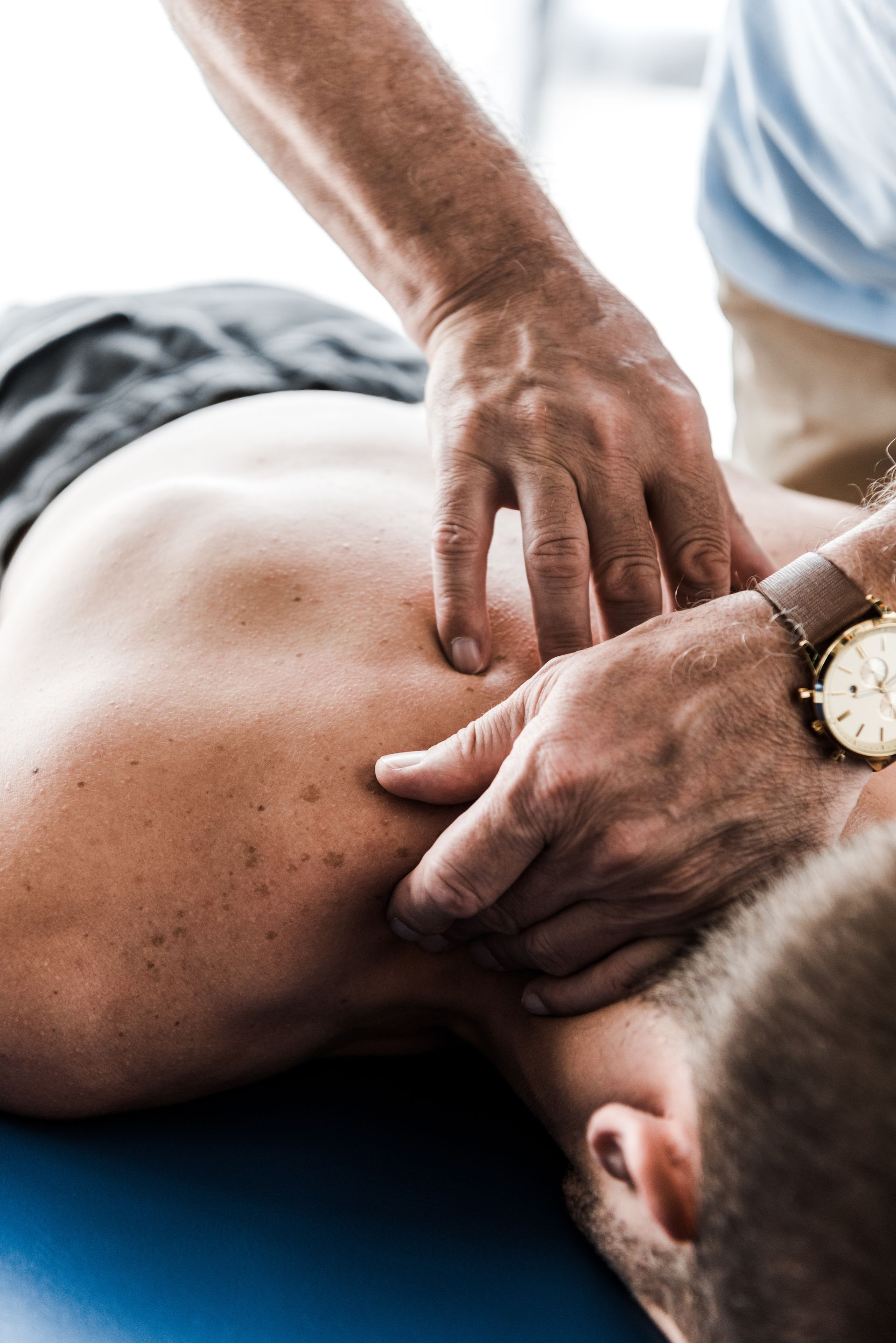 A man is laying on a table getting a massage from a doctor.
