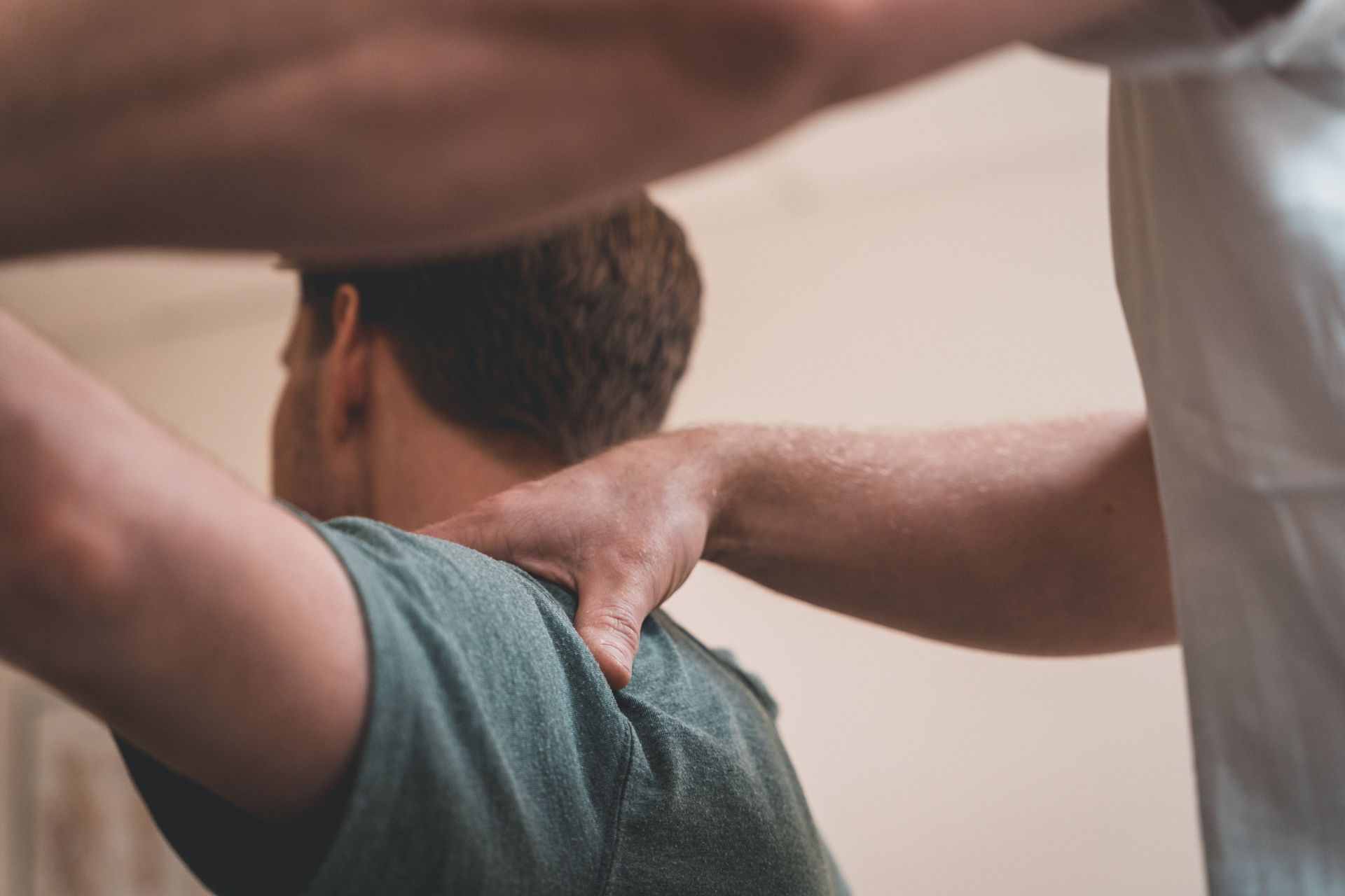 Person receiving a shoulder massage from another person in a neutral indoor setting