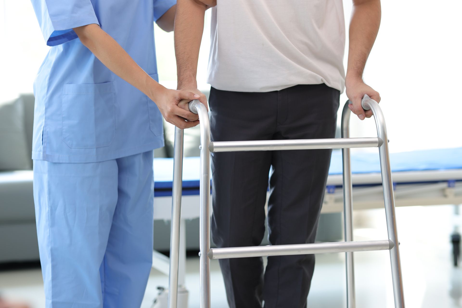 Nurse assisting a patient with a walker in a bright hospital hallway
