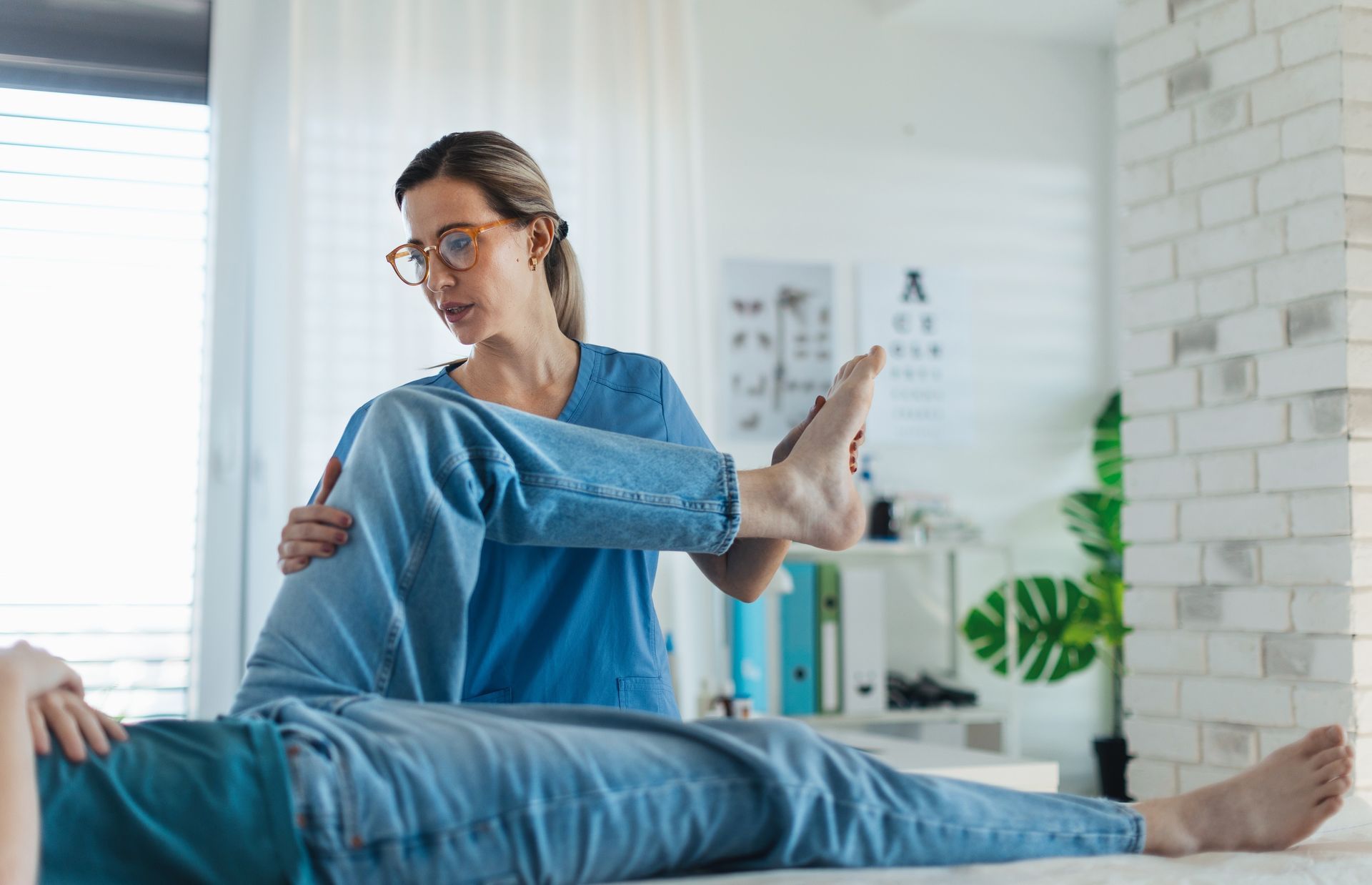 Physical therapist stretching a patient’s leg in a bright clinic room