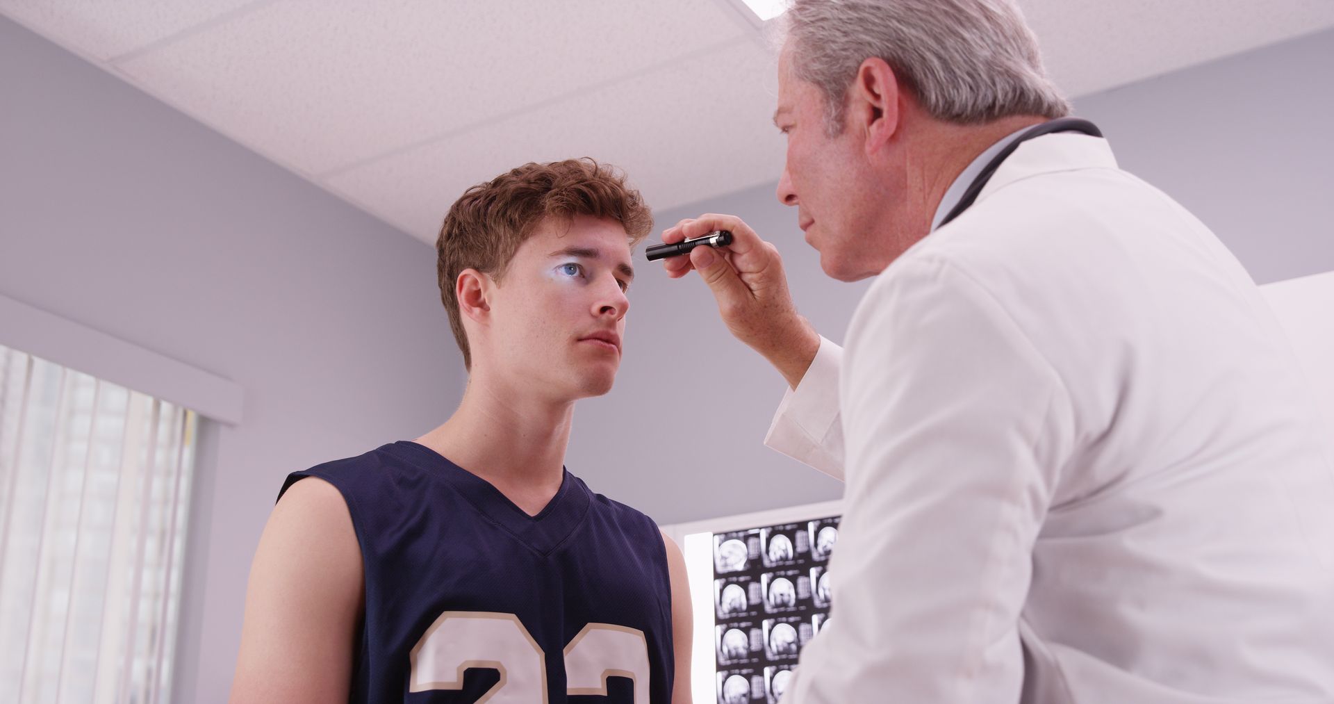 Doctor examining a young athlete’s eye in a medical exam room