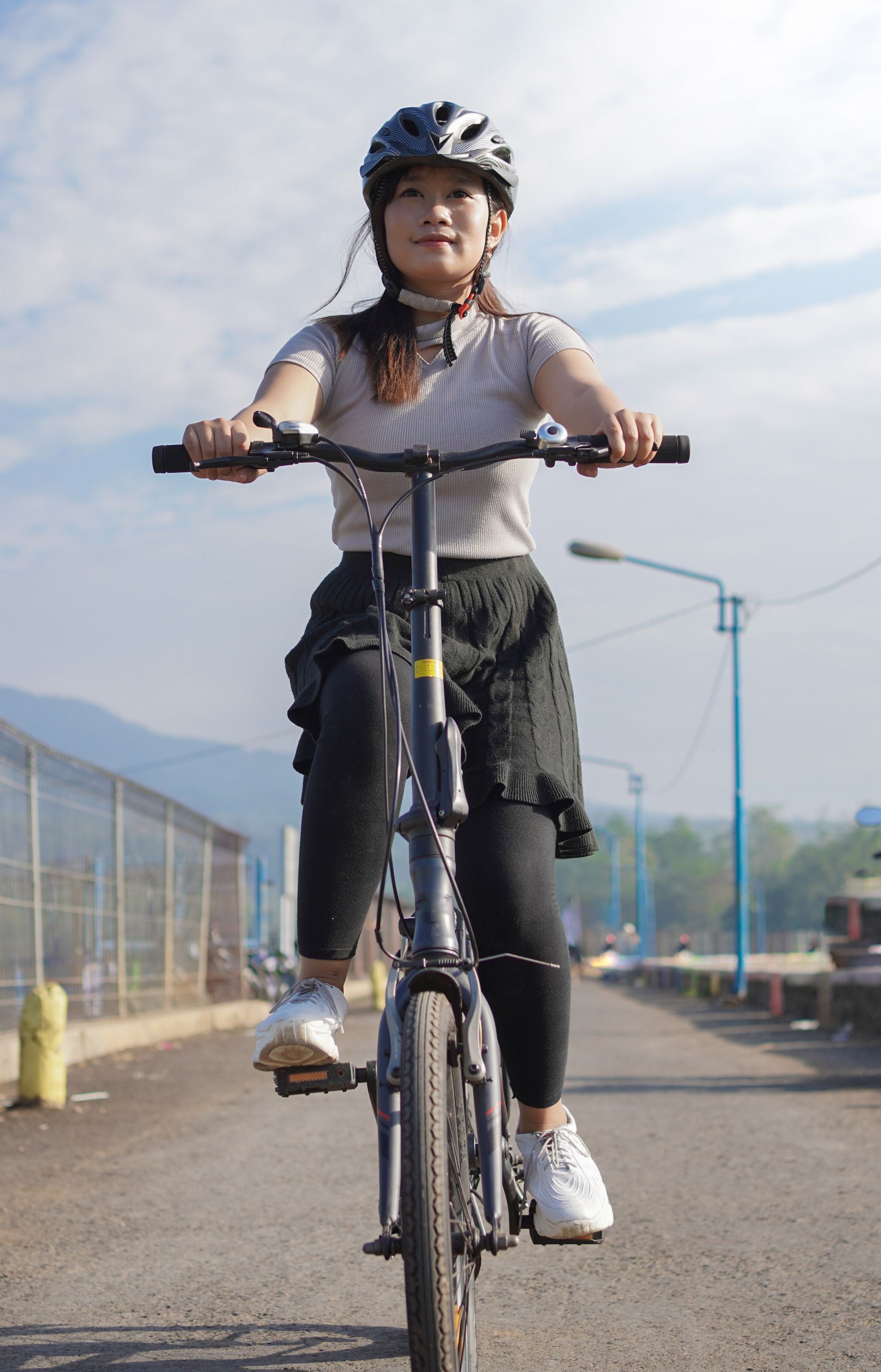 A woman wearing a helmet is riding a bike down a street.