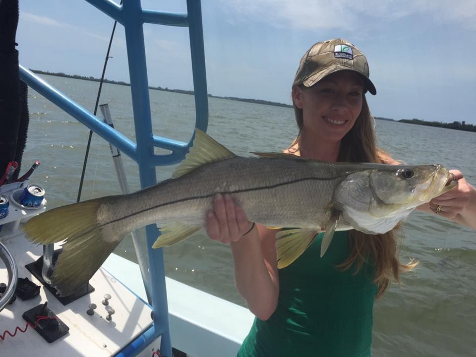 A woman is holding a large fish on a boat