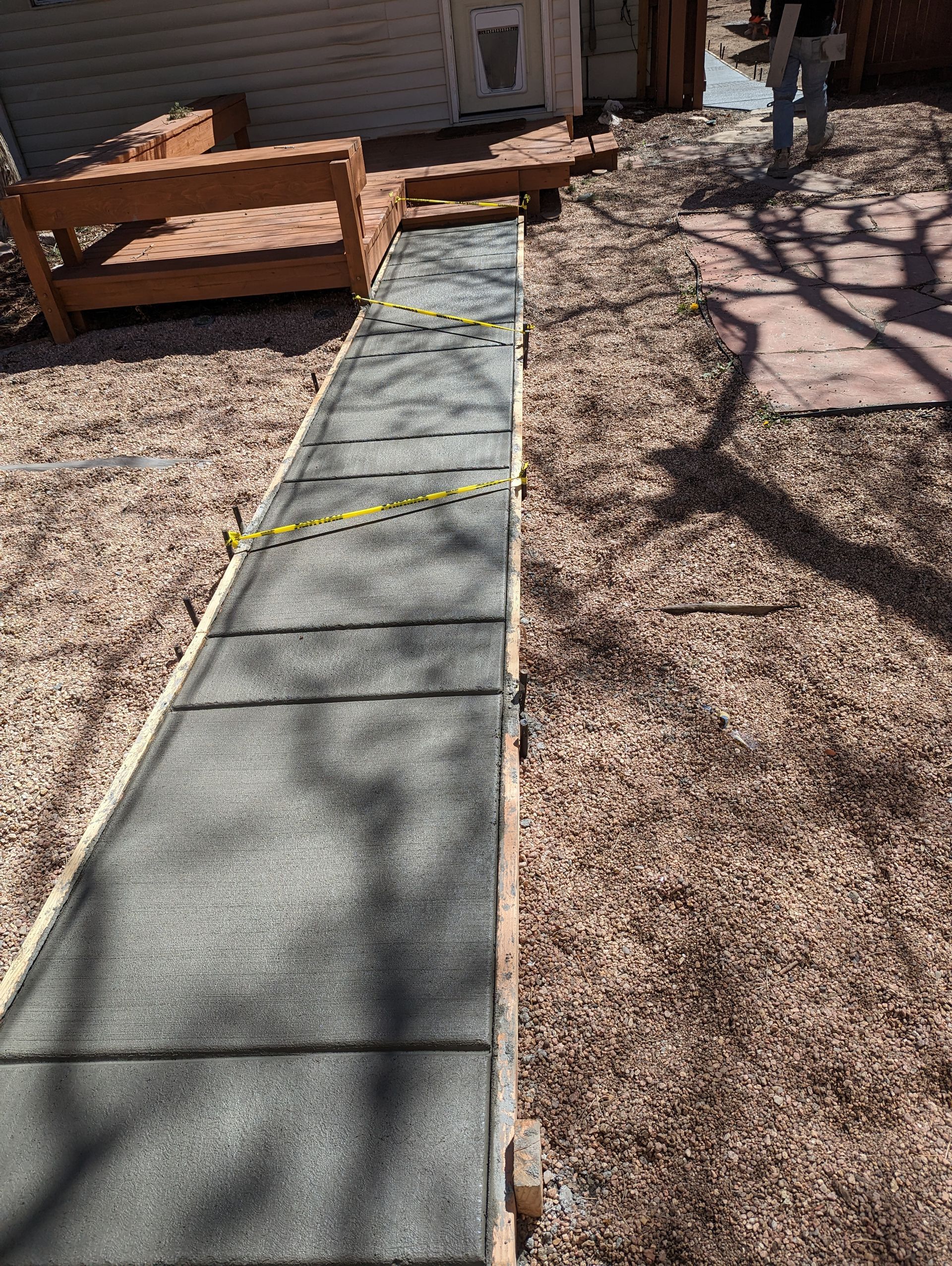 A concrete walkway is being built in a backyard.