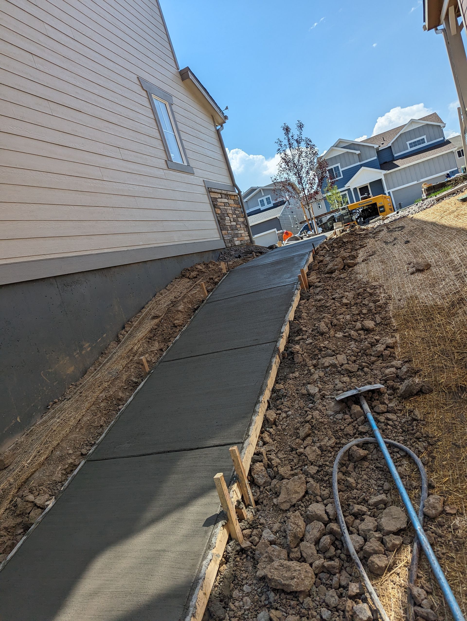 A concrete walkway is being built next to a house.