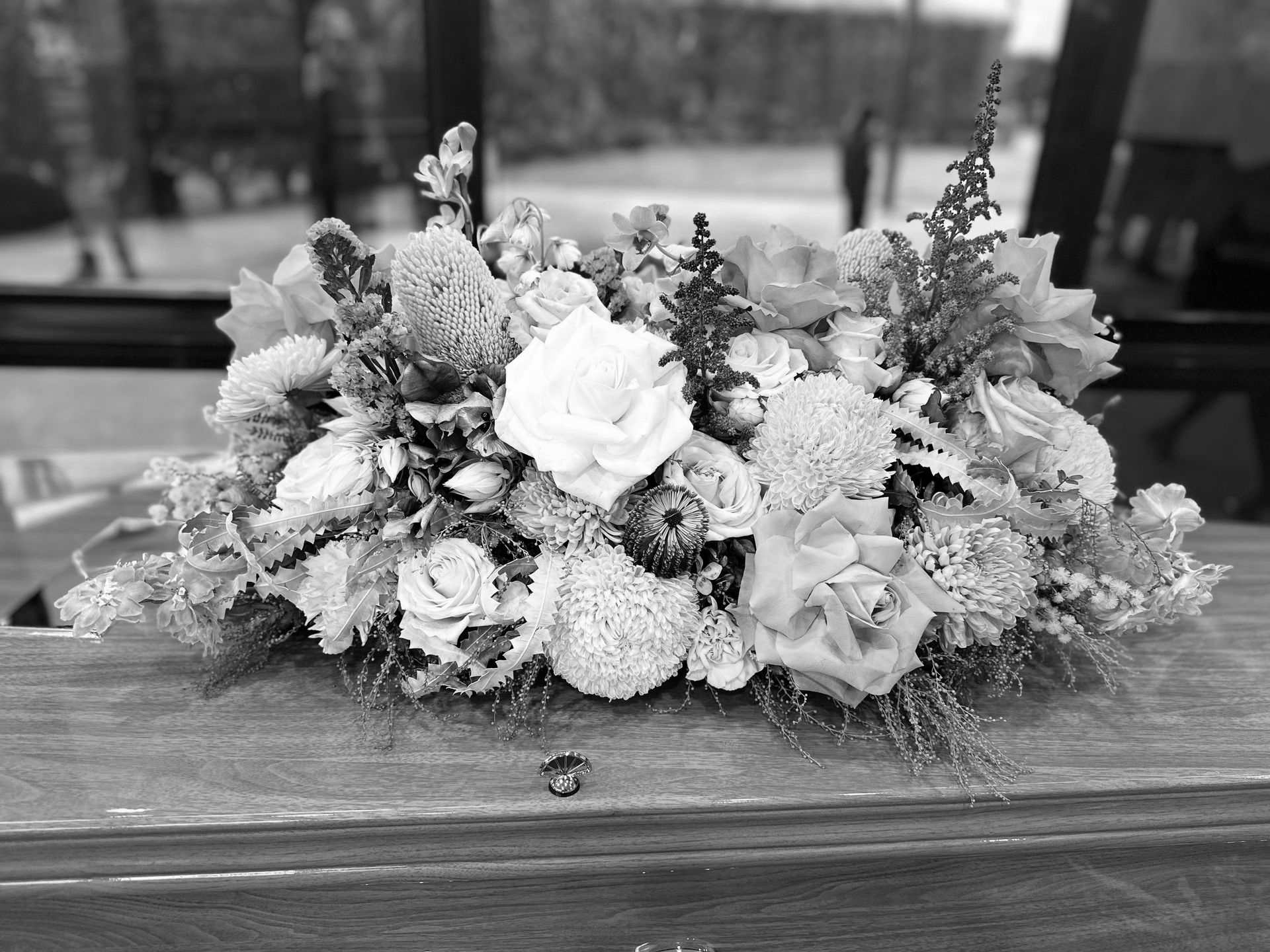 Flower arrangement on a wooden surface, in front of a window.