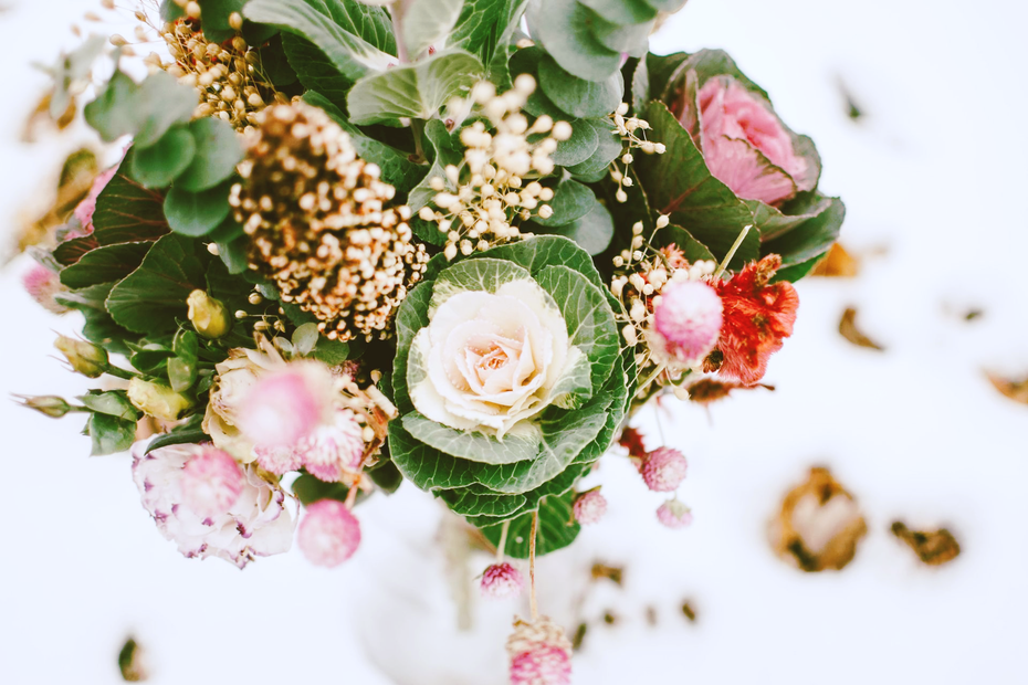 Bouquet of pink and white flowers with green leaves against a snowy background.