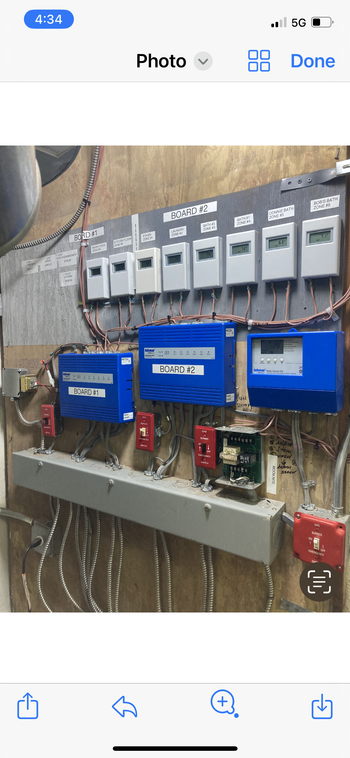 Row of blue electrical control boxes and switches mounted on a wall with cables and wiring.