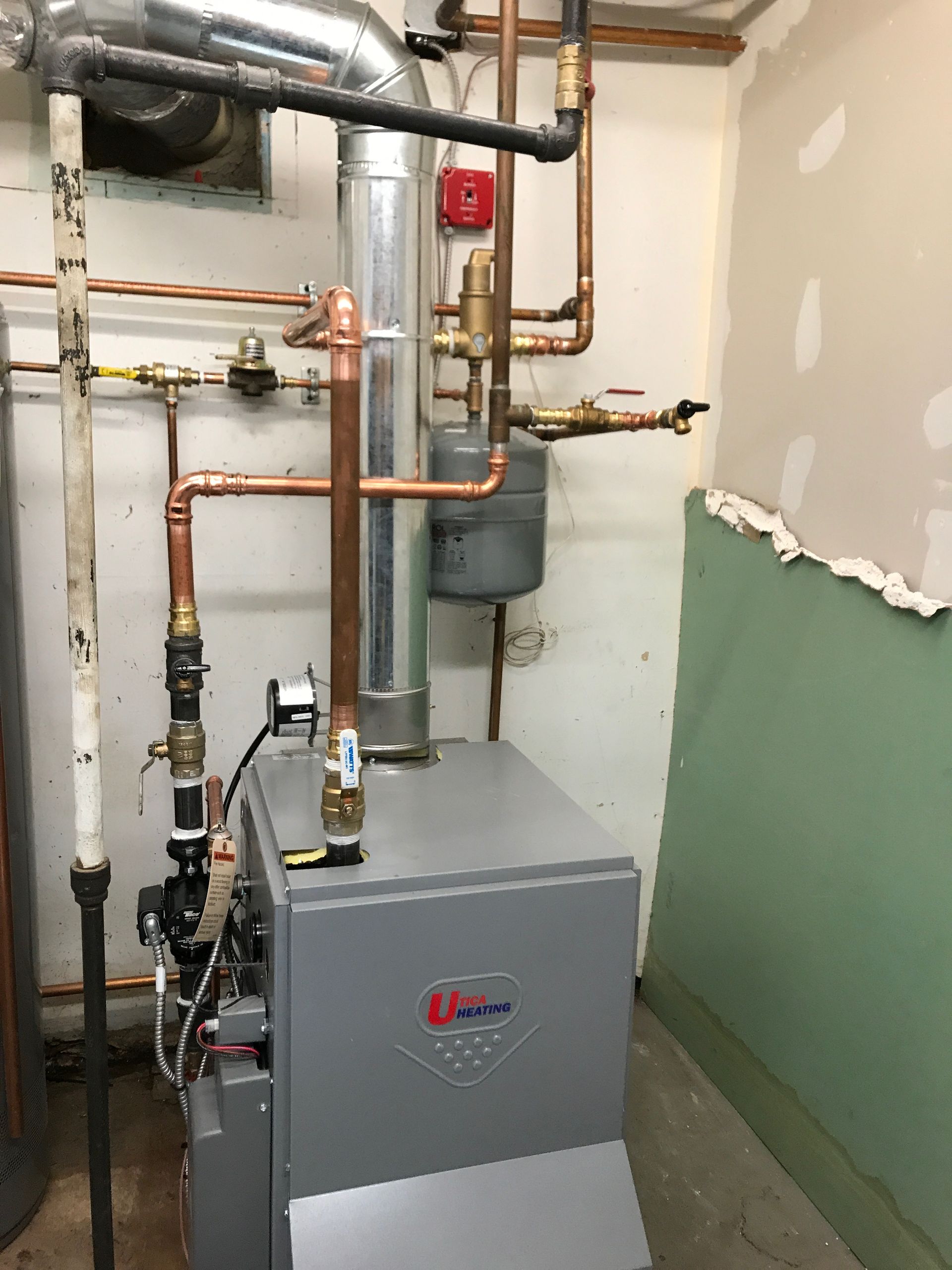 Gas furnace and connected copper piping in a basement utility room.