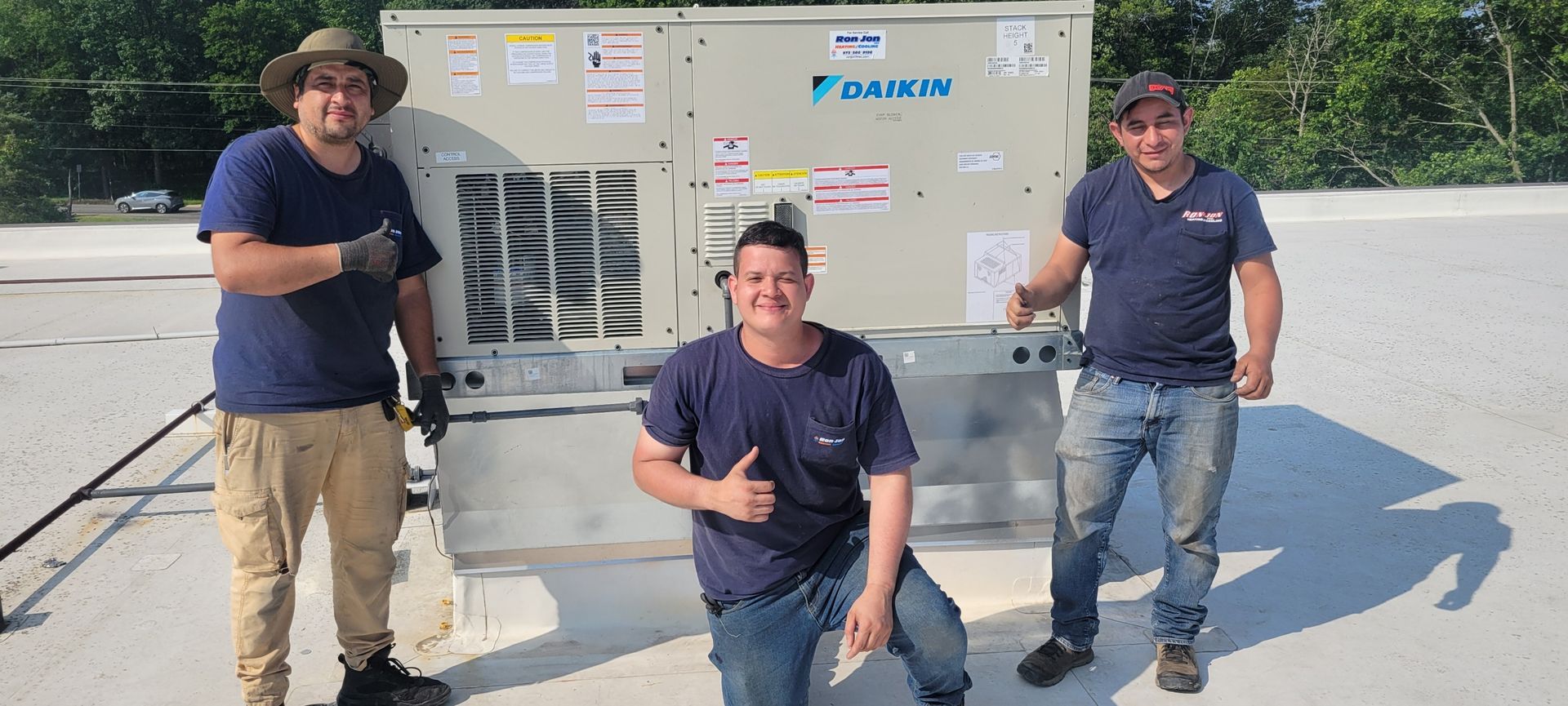 Three men in work uniforms posing beside a large industrial generator outdoors.