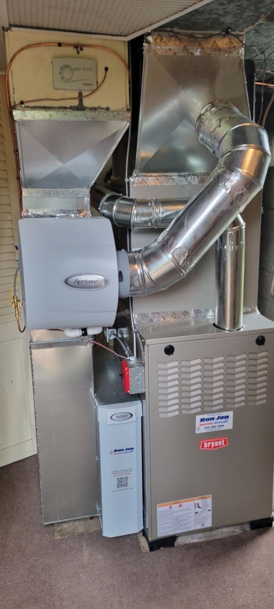 Furnace and metal ductwork installed in a utility closet against unfinished walls
