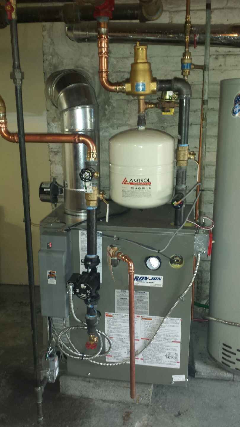 Indoor HVAC unit with copper pipes, white expansion tank, and gray furnace in a utility room