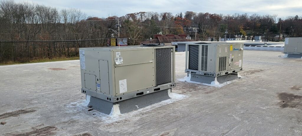 Outdoor HVAC units on a snowy rooftop with trees in the background