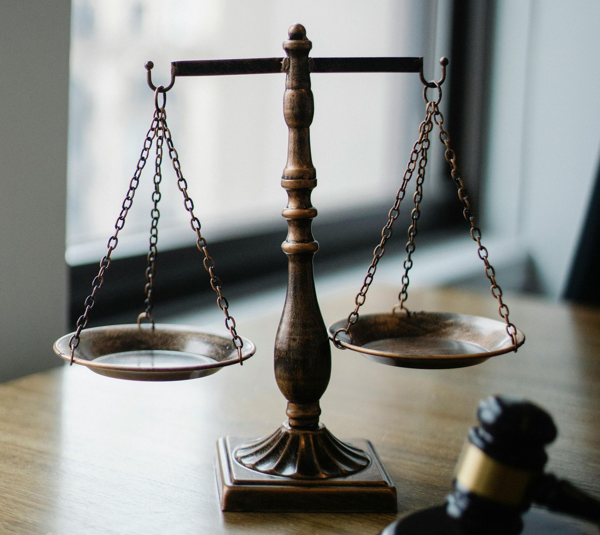 A scale of justice sits on a wooden table next to a judge 's gavel.