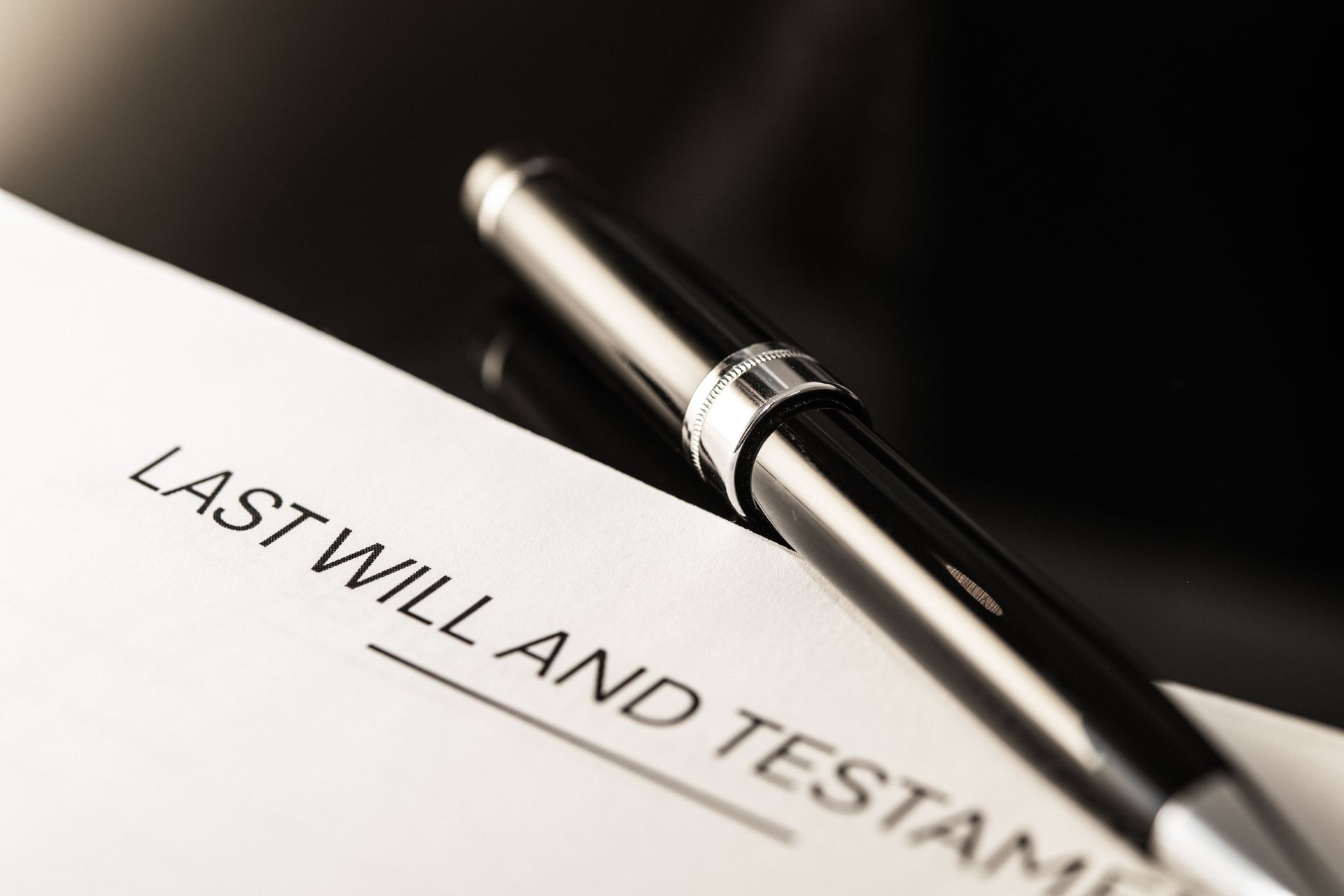 A last will and testament with a pocket watch , pen , and money on a wooden table.