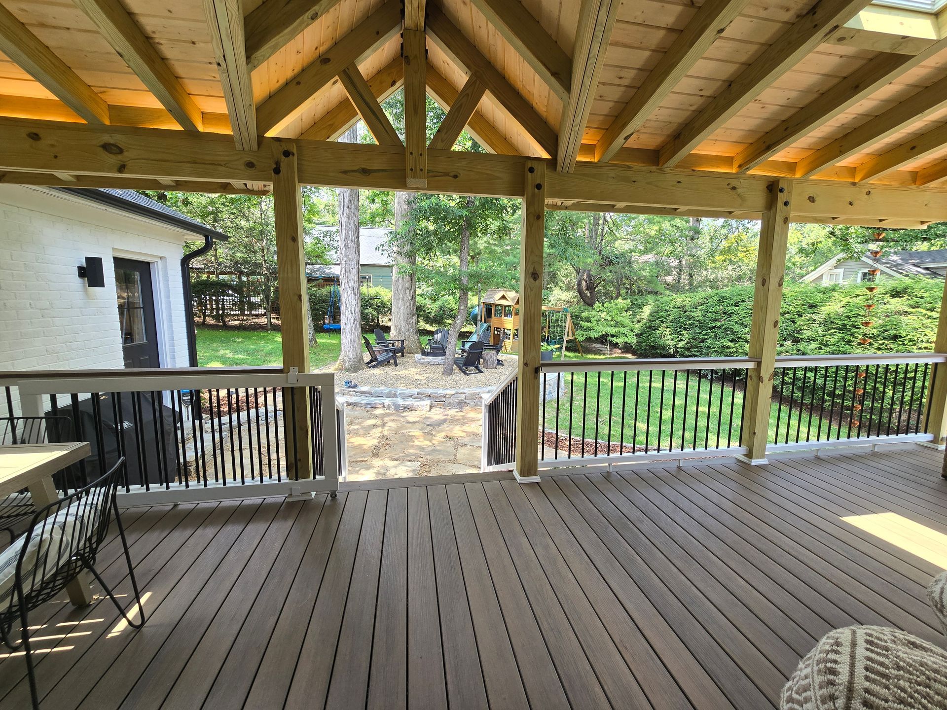 Covered wooden deck overlooking a backyard with decorative railings.