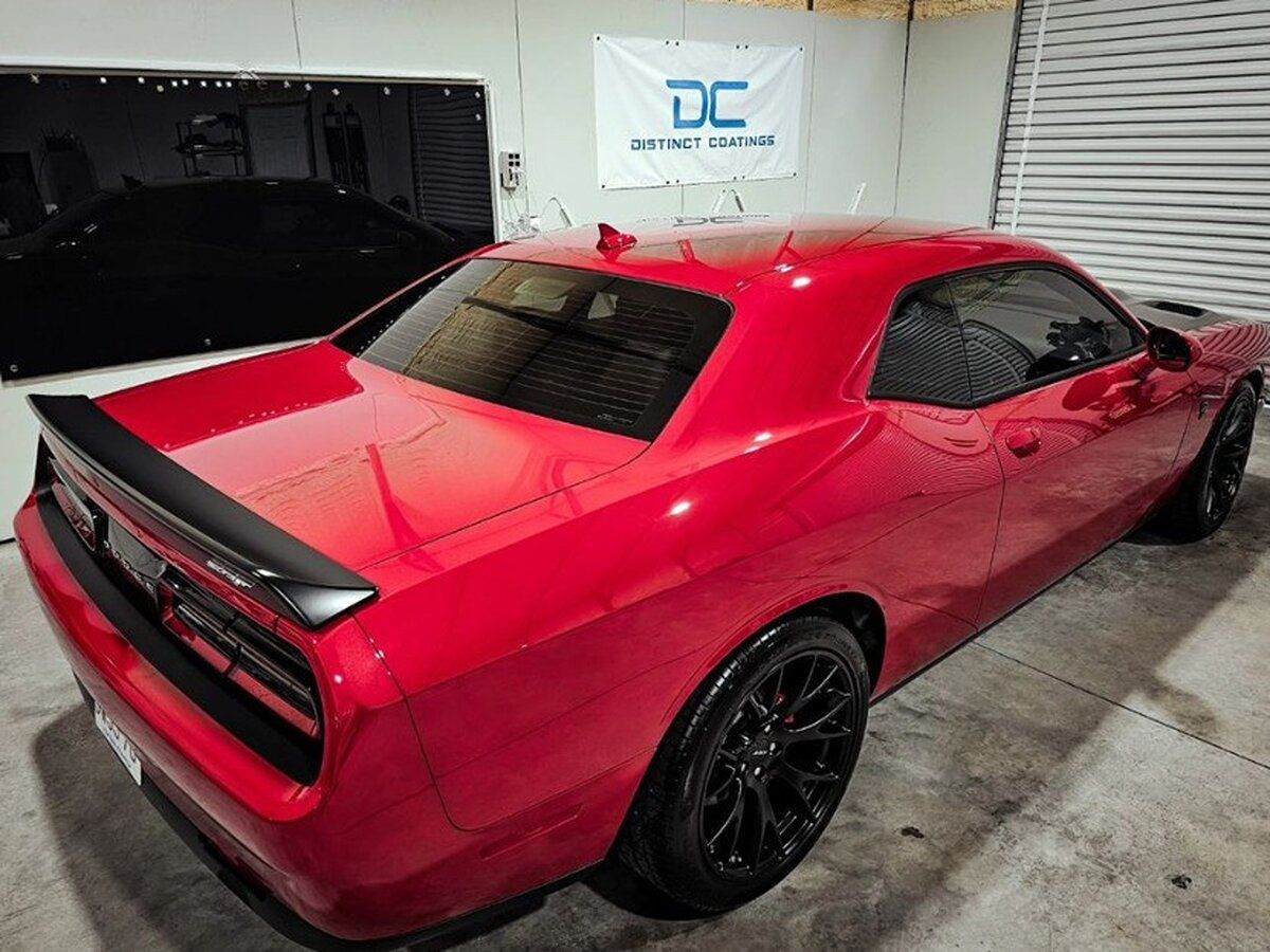 A red dodge challenger is parked in a garage.