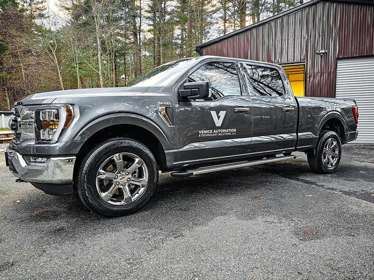 A gray ford f150 truck is parked in front of a garage.