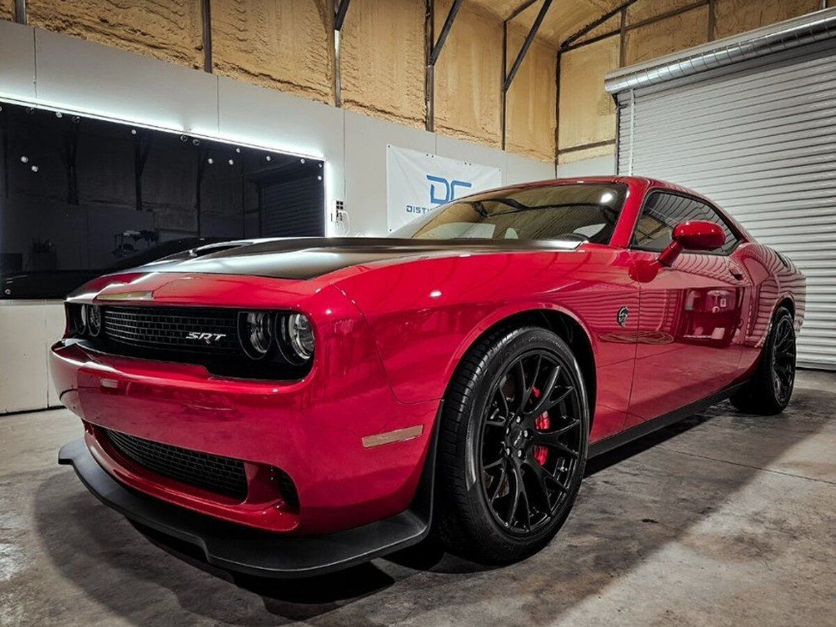 A red dodge challenger is parked in a garage.