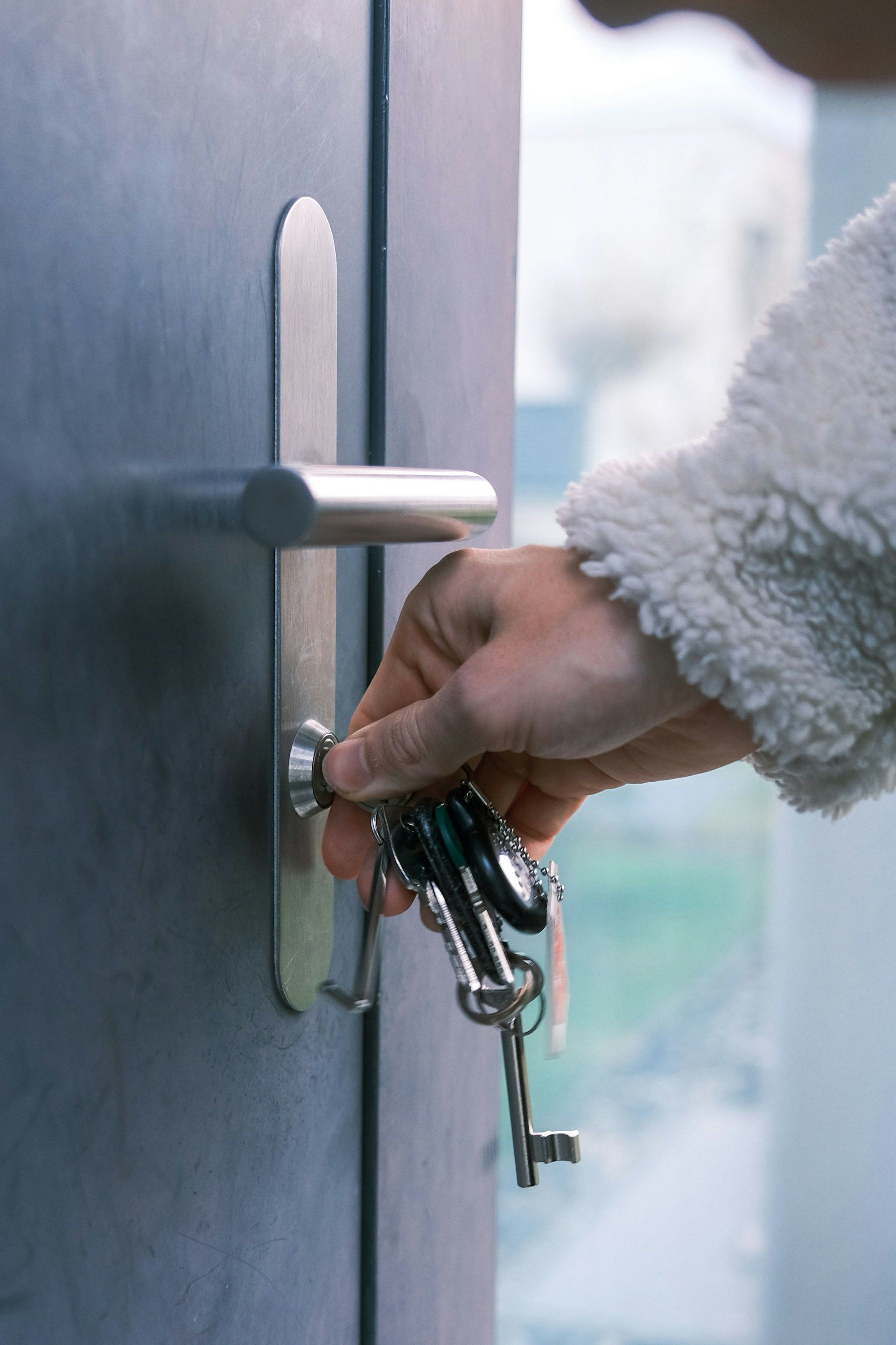 Close-up of a person's hand turning a key in a condo door lock