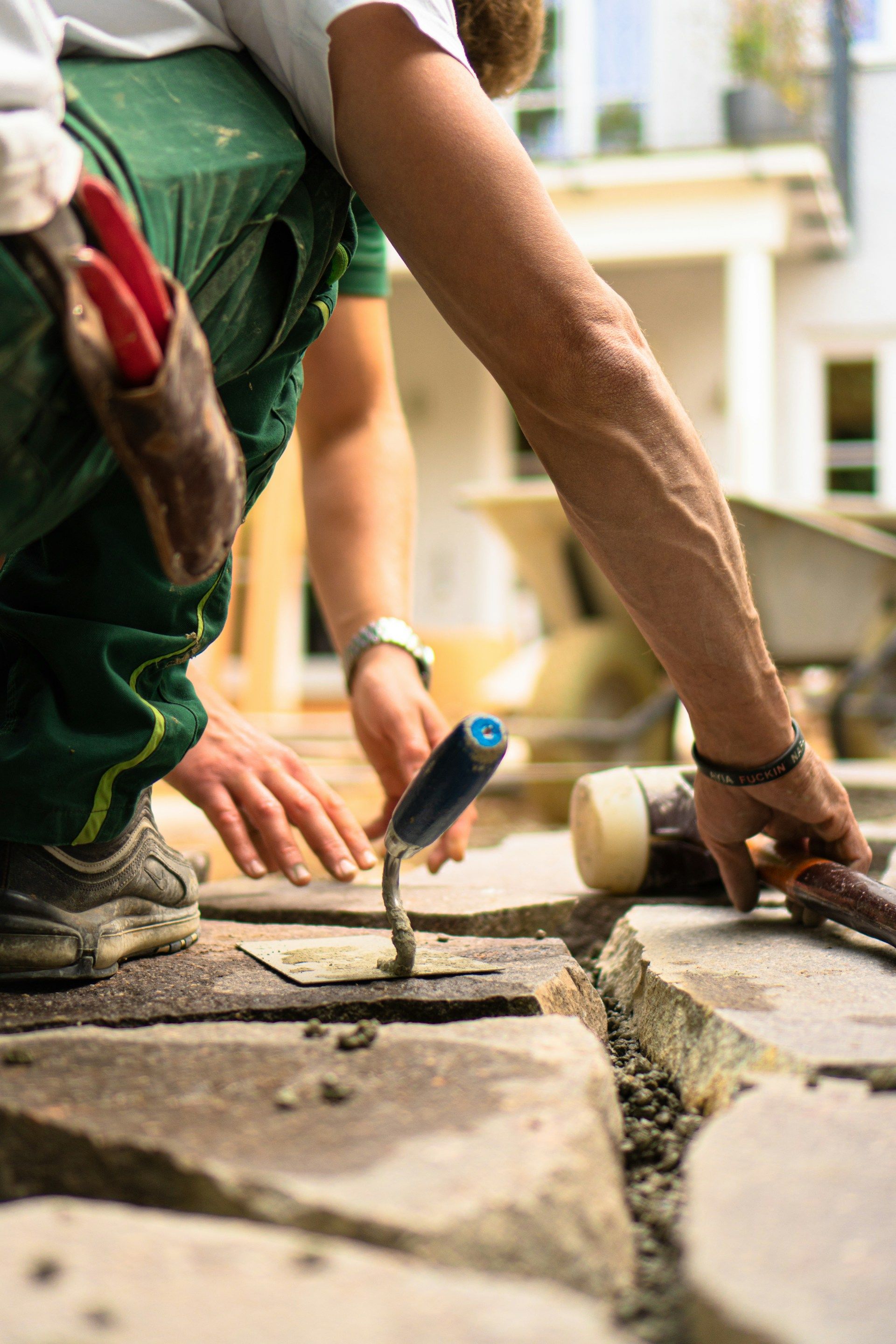 Close up of a tradesman using a trowel to work on paving stones or bricks outdoors