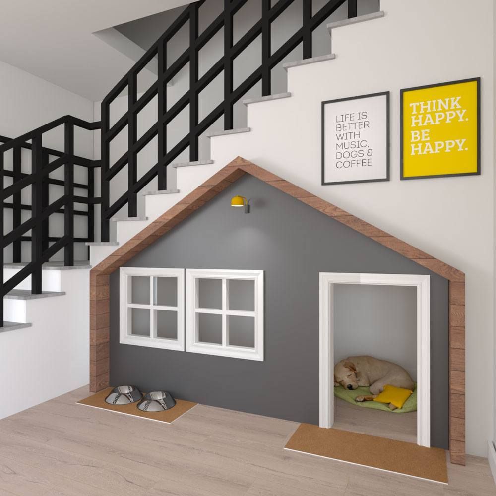A small, house-shaped dog nook built under a staircase, featuring a grey facade, white windows, and a sleeping dog inside.