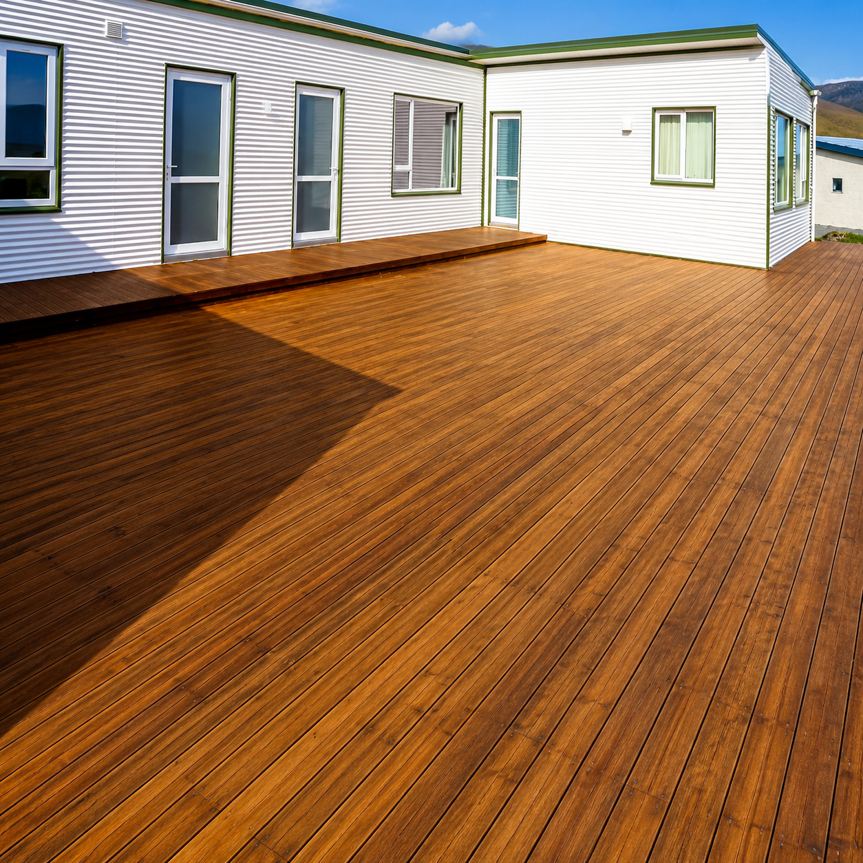 White houses on a wooden deck beneath rocky mountains under a cloudy blue sky