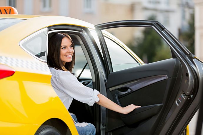 Woman smiling from the back seat of a yellow car with the door open