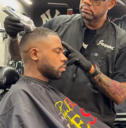 Barber trimming a client's hair with clippers in a barbershop