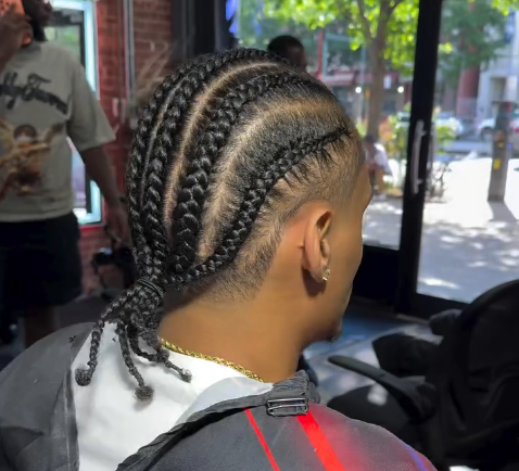 Close-up of a braided hairstyle with cornrows and a low ponytail in a salon chair