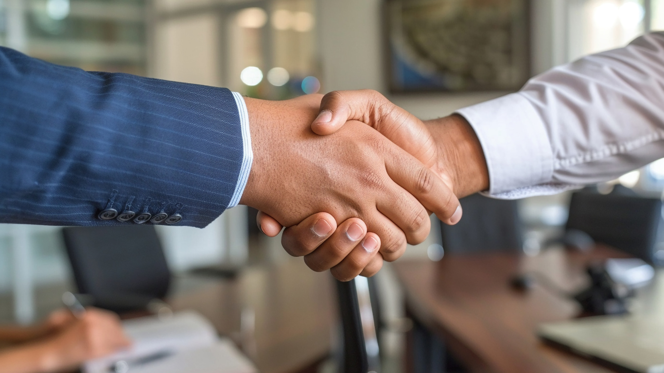 Two people shaking hands in an office setting, sealing a deal or agreement.