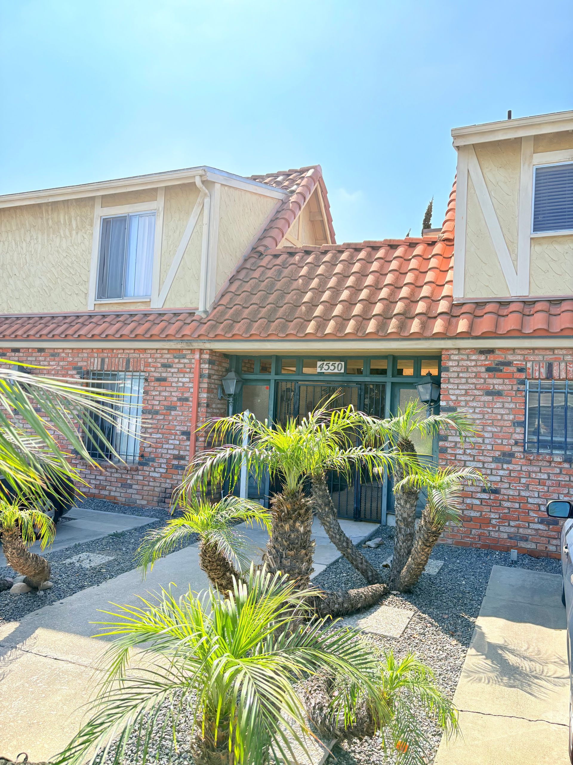 A brick house with a tiled roof and a palm tree in front of it.
