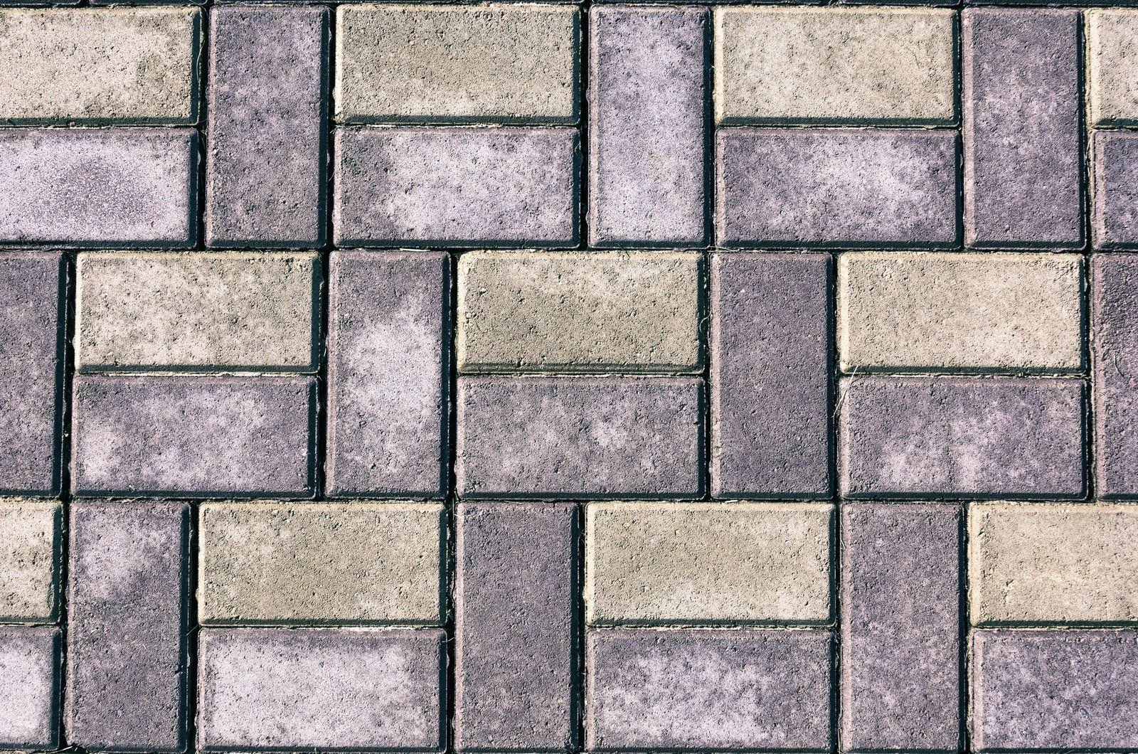 Interlocking brick pavement pattern; alternating gray and light-tan bricks.