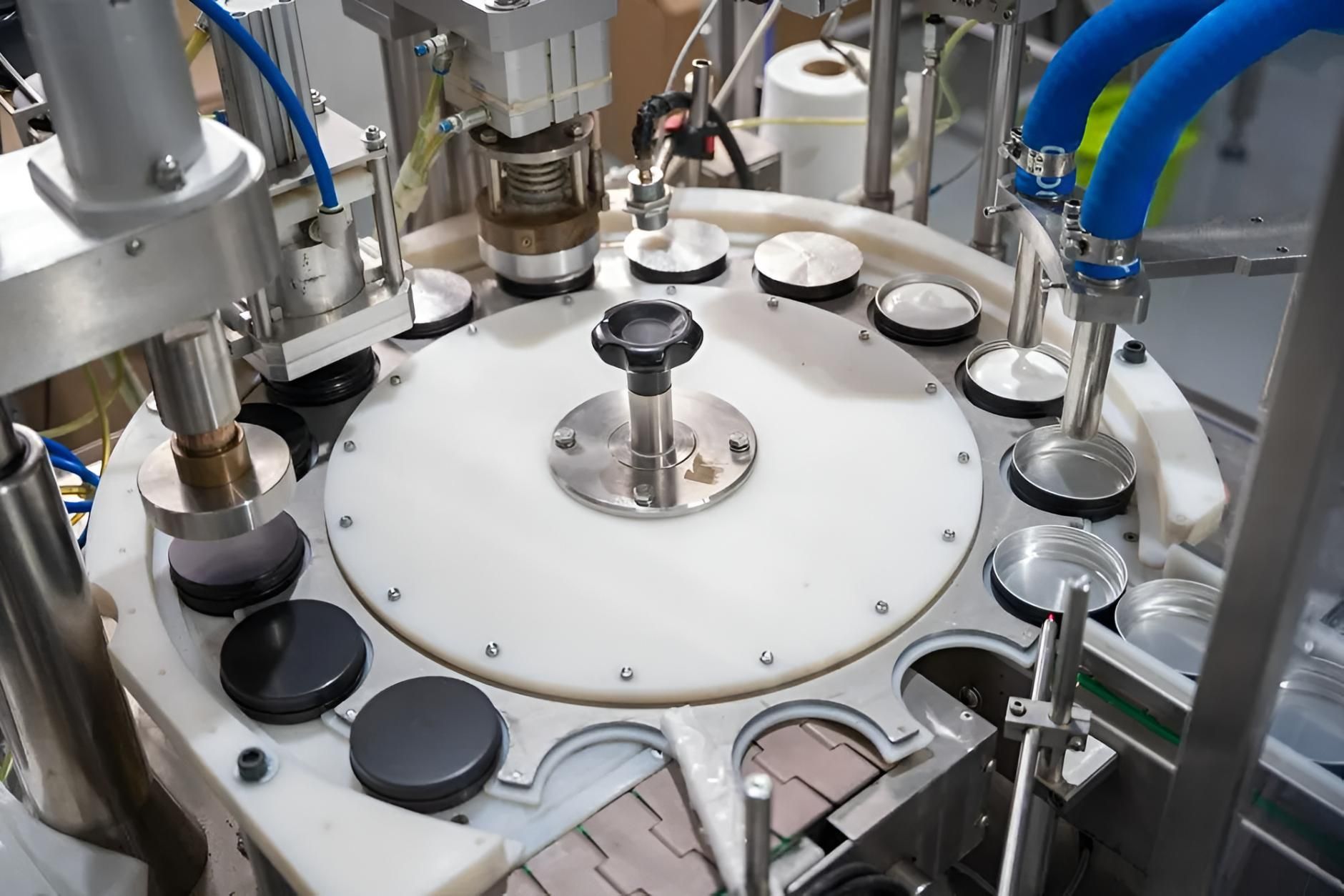 Close-up of an Automated Can-filling Machine With a Rotating White Disc Holding Cans in Place — C & D Manufacturing In Caboolture, QLD