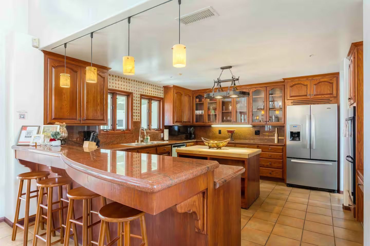 Kitchen with wooden cabinets, granite countertops, and stainless steel refrigerator.