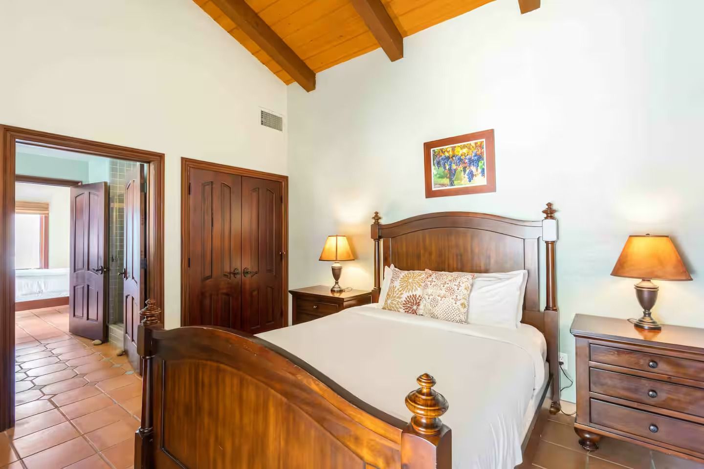 Bedroom with wooden bed, nightstands, closet, and open doorway to another room.