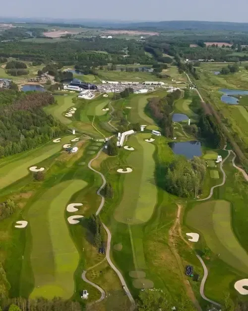 Aerial view of a lush golf course with winding fairways, sand bunkers, and ponds on a clear day
