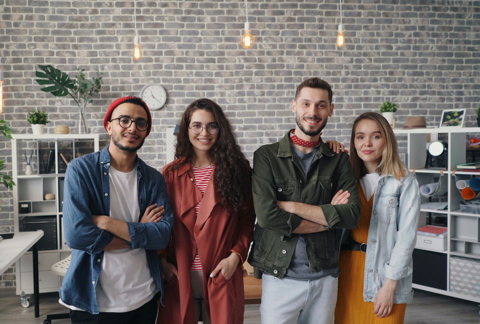 Four smiling coworkers standing in a modern office. Young professionals, savings, investments, income protection, a first home | CFP advice helps