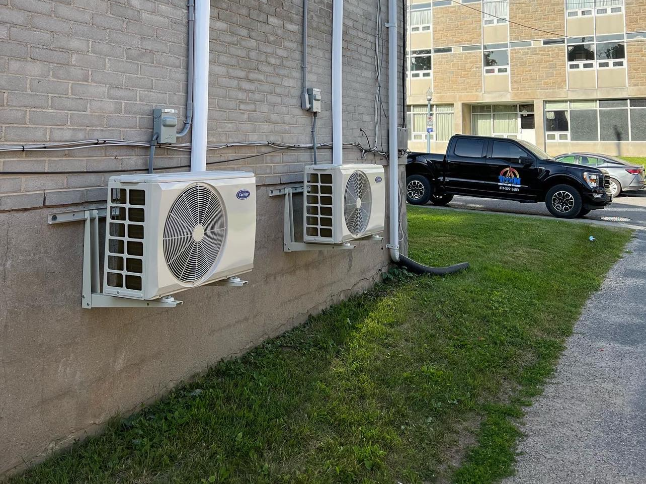 Three air conditioners are mounted on the side of a building.