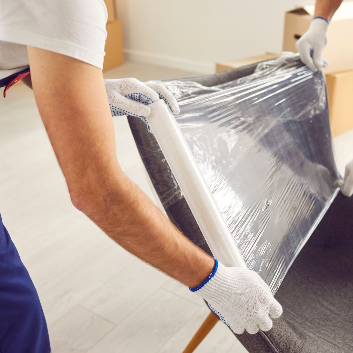 A man is wrapping a chair with plastic wrap