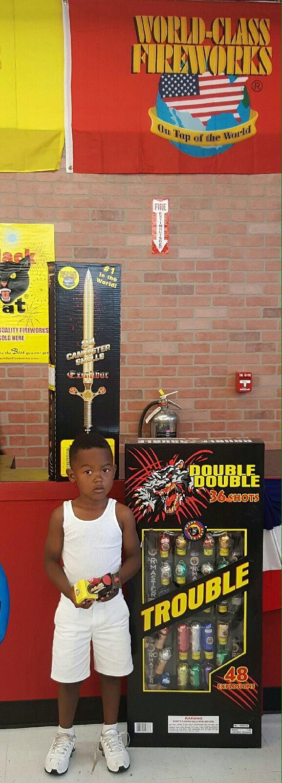 A young boy is standing in front of a box of trouble fireworks