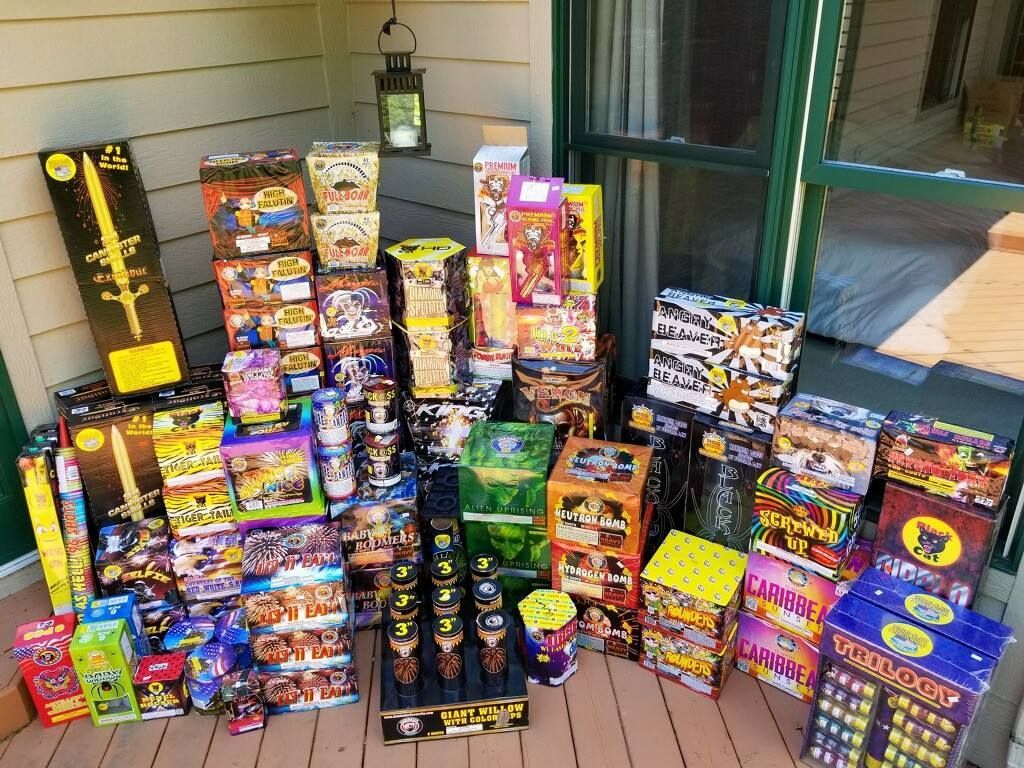 A bunch of fireworks are stacked on top of each other on a porch.